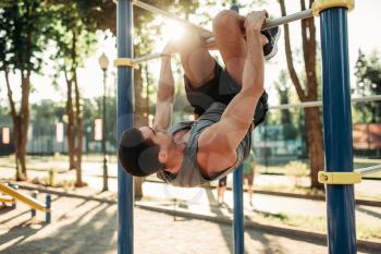 Athletic man doing exercise on horizontal bar on outdoor fitness workout. Strong sportsman on sport training