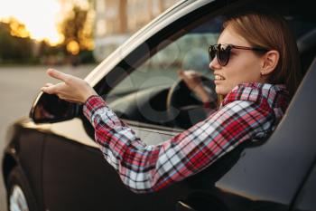 Female car driver in sunglasses, boorish behavior.  Woman in vehicle, aggressive automobile driving concept