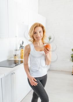 Sporty woman throws up an orange, fit breakfast on the kitchen. Female person at home in the morning, healthy nutrition and lifestyle