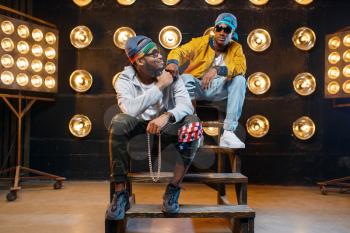 Two black rappers in sunglasses, perfomance on stage with spotlights on background. Rap performers on scene with lights, underground music, urban style