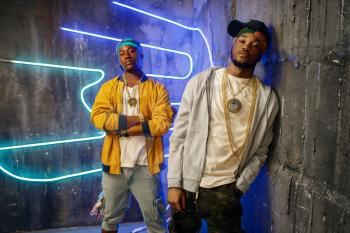 Two black rappers, perfomance in club with neon lights on background. Rap performers in subway, underground music concert