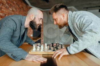 Chess players look into each other's eyes. Two chessplayers finished intellectual tournament indoors. Chessboard on wooden table