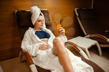 Sexy lady in robe and towel on the head relaxing with cocktail in spa chair. Relaxation leisure, healthy lifestyle, attractive woman in beauty salon