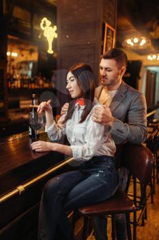 Man and woman relax, couple at wooden bar counter. Lovers leisures in pub, husband and wife relaxing together in nightclub
