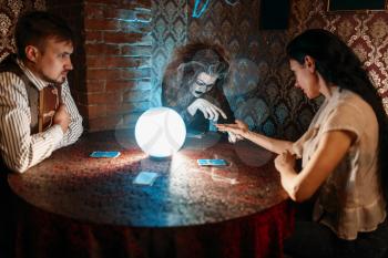 Female foreteller guessing by hand over a crystal ball, witchcraft. Scary witch reads a magic spell, young woman on spiritual seance