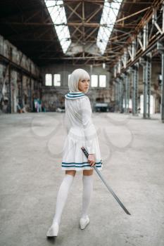 Sexy anime style blonde woman with sword, back view. Cosplay fashion, japanese culture, doll with blade on abandoned factory