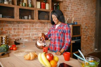 Black woman prepares coffee on breakfast on the kitchen. African female person preparing vegetable salad at home