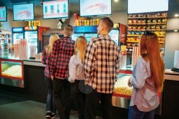 Audience choosing food in cinema bar before the showtime, back view. Male and female youth in movie theater