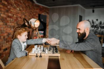 Clever schoolgirl wins the game of chess with man. Young girl at the chessboard, female kid plays logic game