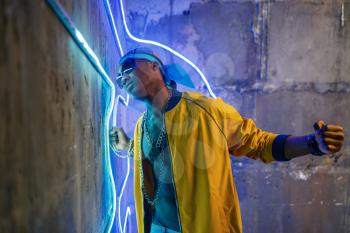 Black rapper in underpass neon lights on background. Rap performer in club with grunge walls, underground