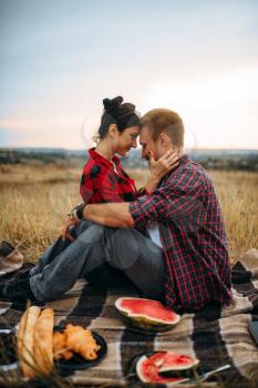 Love couple hugs, picnic in summer field. Romantic junket, man and woman leisure together, happy family weekend