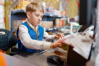 Little boy in uniform at the register playing salesman, playroom. Kids plays sellers in imaginary supermarket, sales profession learning