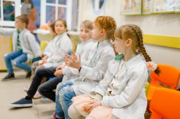 Children in uniform learning doctor profession in classroom, playroom. Kids plays medicine worker in imaginary hospital, childish dream