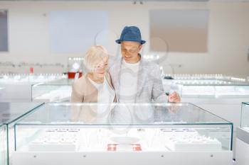 Love couple looking on jewels in jewelry store. Man and woman choosing wedding rings. Future bride and groom in the jewellery shop