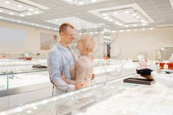 Love couple looking on jewels in jewelry store. Man and woman choosing wedding rings. Future bride and groom in jewellery shop