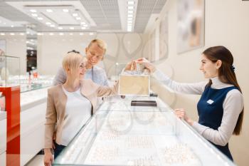 Happy love couple makes purchase in jewellery shop. Male and female consumers looking on jewels in jewelry store. Man and woman choosing wedding rings