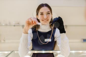 Female seller demonstrating gold decoration in jewellery shop