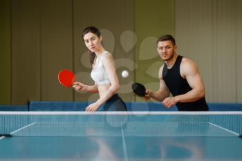Group of friends playing table tennis ping pong indoors. People in sportswear holds rackets and plays table-tennis in gym