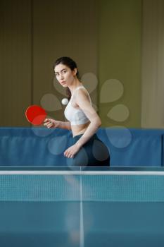 Woman with racket and ball playing ping pong indoors. Female person in sportswear, training in table tennis club