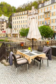 Cosy outdoor cafe with rattan furniture and view on river, Karlovy Vary, Czech Republic, Europe. Old european town, famous place for travel
