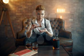 Woman in strict clothes smoking cigar at the table, retro fashion, gangster style. Vintage business lady
