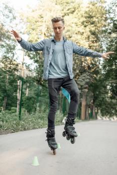Roller skating, male teenager rolling on one leg in park. Urban roller-skating, active extreme sport outdoors