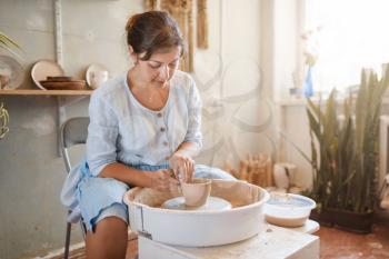 Female master making a pot on pottery wheel. Woman molding a bowl. Handmade ceramic art, tableware from clay
