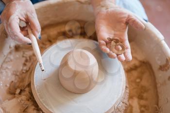 Wet pot on pottery wheel in workshop. Woman molding a bowl. Handmade ceramic art, tableware from clay, traditional hobby