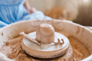 Wet pot on pottery wheel in workshop. Woman molding a bowl. Handmade ceramic art, tableware from clay, traditional hobby