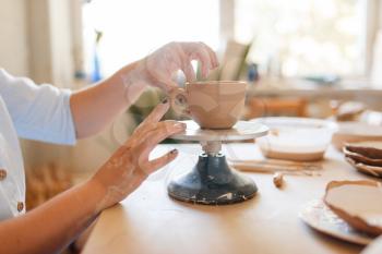 Female potter skins pot with her fingers, pottery workshop. Woman molding a bowl. Handmade ceramic art, tableware from clay