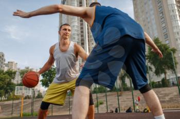 Two players in the center of the basketball field on outdoor court. Male athletes in sportswear play the game on streetball training
