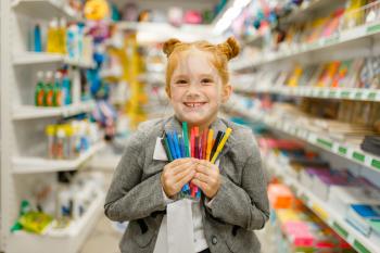 Little school girl holds colorful markers, shopping in stationery store. Female child buying office supplies in shop, schoolchild in supermarket