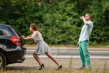 Man and woman pushing broken car on road, breakdown. Crashed automobile or emergency accident with vehicle, trouble with engine on highway