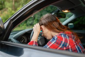 Female driver with blooded face sitting in the car after accident on road. Automobile crash, blood on the woman's face. Broken automobile or damaged vehicle, auto collision on highway