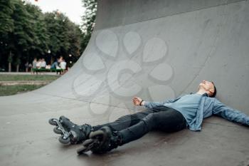 Roller skating, male skater lying on the ramp. Urban roller-skating, active extreme sport outdoors, youth leisure, rollerskating lifestyle