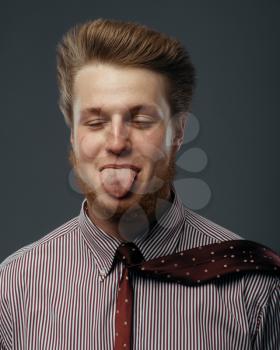 Strong wind blowing in male face, man shows tongue, funny emotion. Powerful air flow blows on businessman on black background