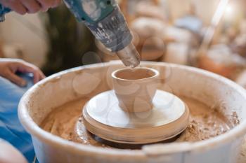 Master dries a pot on pottery wheel, closeup view. Woman molding a bowl. Handmade ceramic art, tableware from clay