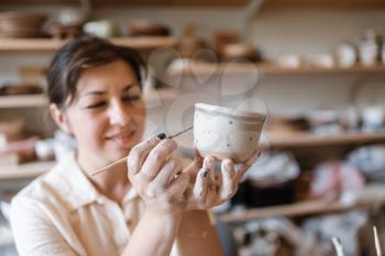 Female master paints a pot, pottery workshop. Woman molding a bowl. Handmade ceramic art, clay tableware