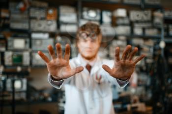 Strange scientist showing scorched hands in laboratory. Electrical testing tools on background. Lab equipment, engineering workshop