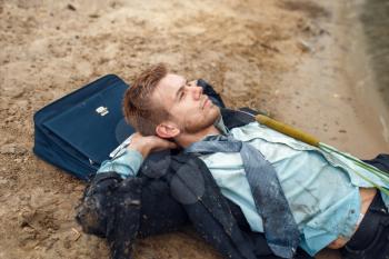 Office worker in torn suit resting on the beach on desert island. Business risk, collapse or bankruptcy concept