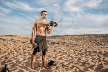 Sportsman doing exercises with weights in desert at sunny day. Strong motivation in sport, strength outdoor training