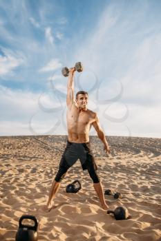 Sportsman doing exercises with weights in desert at sunny day. Strong motivation in sport, strength outdoor training