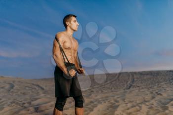 Male athlete in sportswear, fit cross workout in desert at sunny day. Strong motivation in sport, strength outdoor training