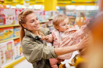 Mother with her little girl choosing plush dog in kids store. Mom and child buying toys in supermarket together, family shopping
