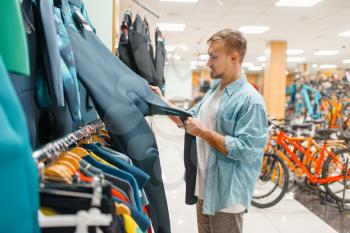 Man choosing cycling suit, shopping in sports shop. Summer season extreme lifestyle, active leisure store, customers buying bicycle equipment