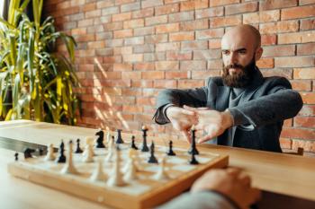 Male chess players on competition, board with figures. Two chessplayers begin the intellectual tournament indoors. Chessboard on wooden table, strategy game