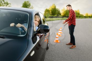 Instructor is happy with the driving of his female student between cones, lesson in driving school. Man teaching lady. Driver's license education