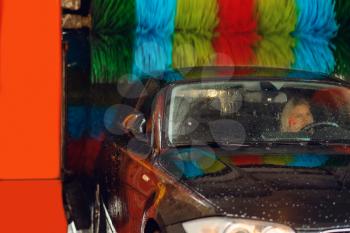 Woman in auto on automatic car wash with colorful brush, nobody. Vehicle cleaning service or business, express carwash station