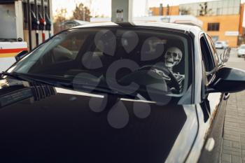 Human skeleton in car, fueling on gas station, fuel refill. Petrol, gasoline or diesel refuel service, petroleum refueling