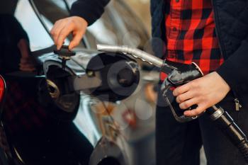 Man inserts the gun into the car tank on gas station, closeup view, fuel filling. Petrol fueling, gasoline or diesel refuel service
